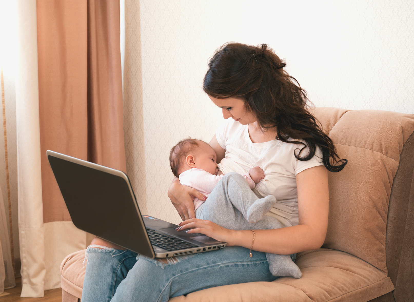 Beautiful Young Mother Working With Laptop Computer And Breastfeeding, Holding And Nursing Her Newborn Baby At Home. Mom - Business Woman.